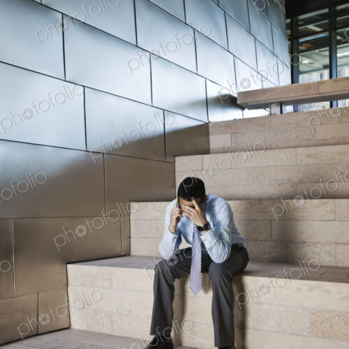 Businessman in a stressful situation while on a cell phone in the lobby of a large… Businessman in a stressful situation while on a cell phone in the lobby of a large…