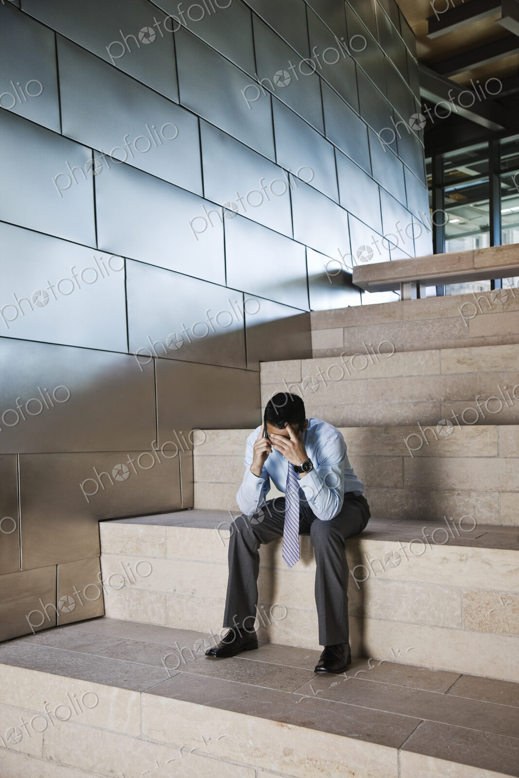 Businessman in a stressful situation while on a cell phone in the lobby of a large…