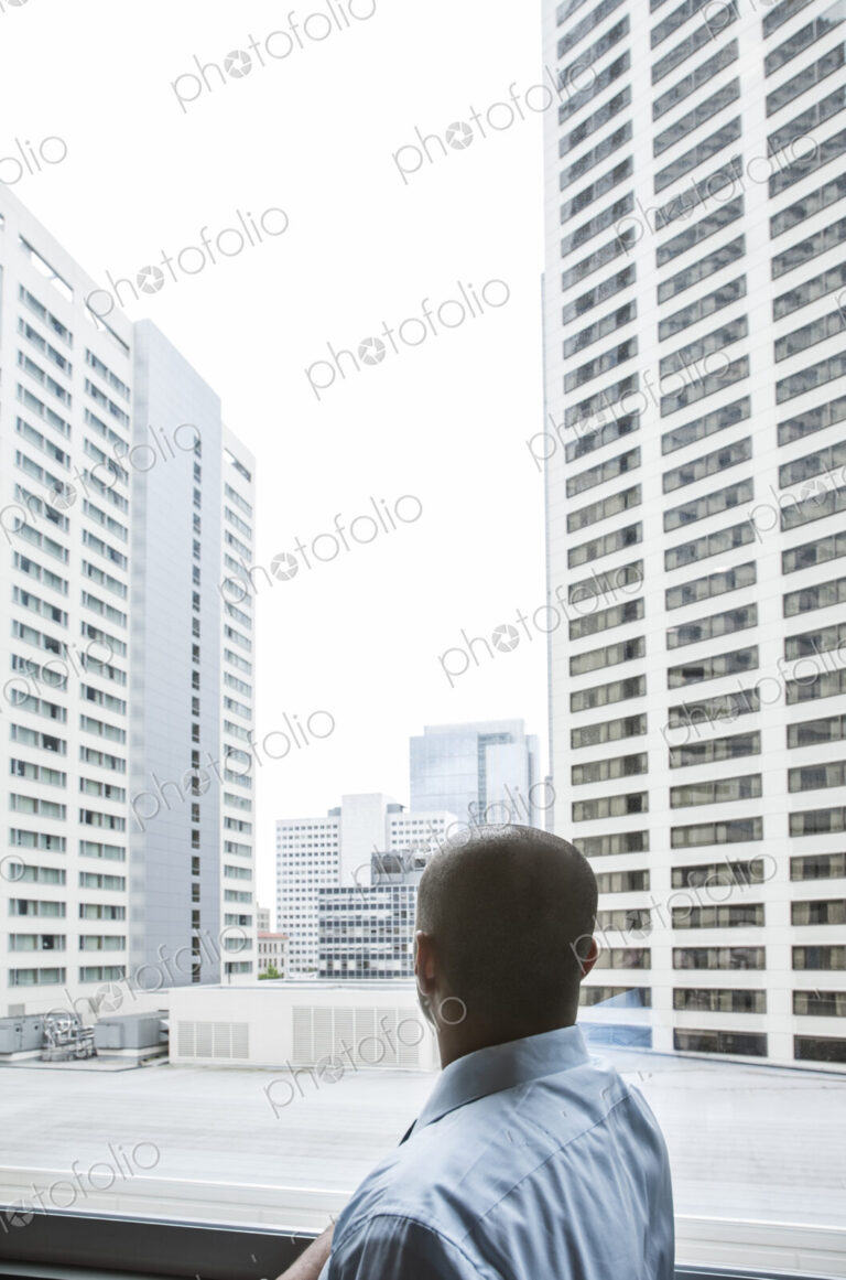 Businessman looking out a window at a cityscape of tall buildings