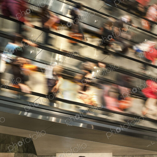 Businessman on a notebook computer near an escalator full of people. Businessman on a notebook computer near an escalator full of people.
