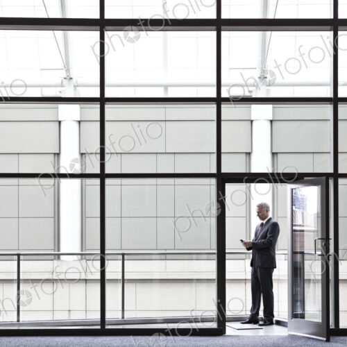 Businessman on a small office balcony checking his phone.