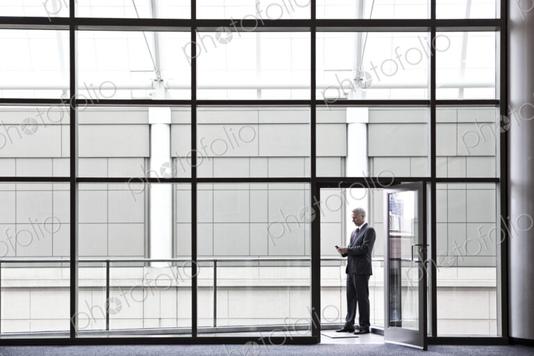 Businessman on a small office balcony checking his phone.