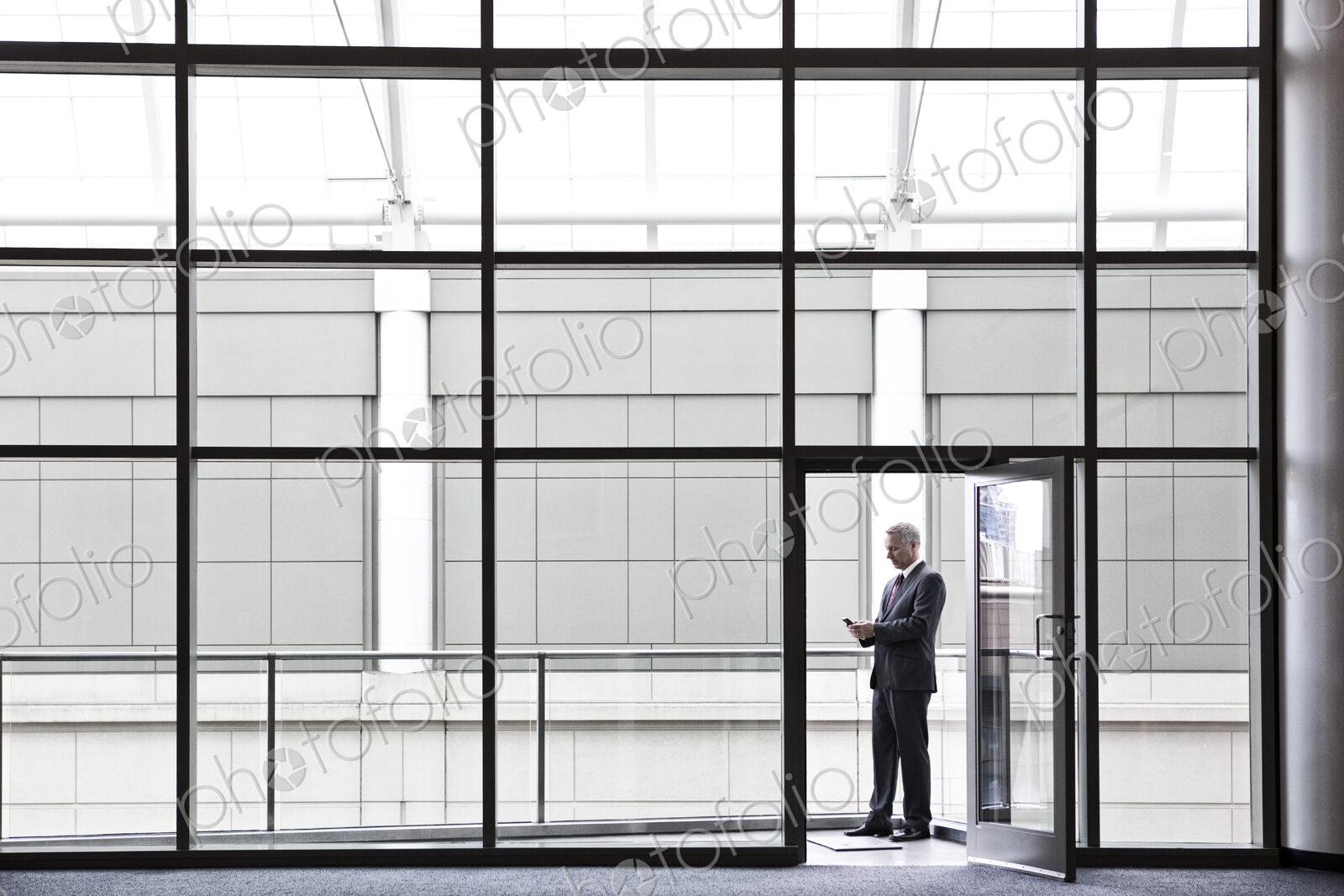 Businessman on a small office balcony checking his phone.