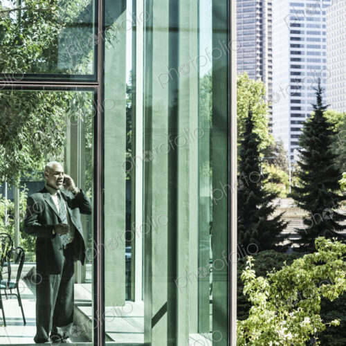 Businessman on the phone standing in a glassed in walkway.