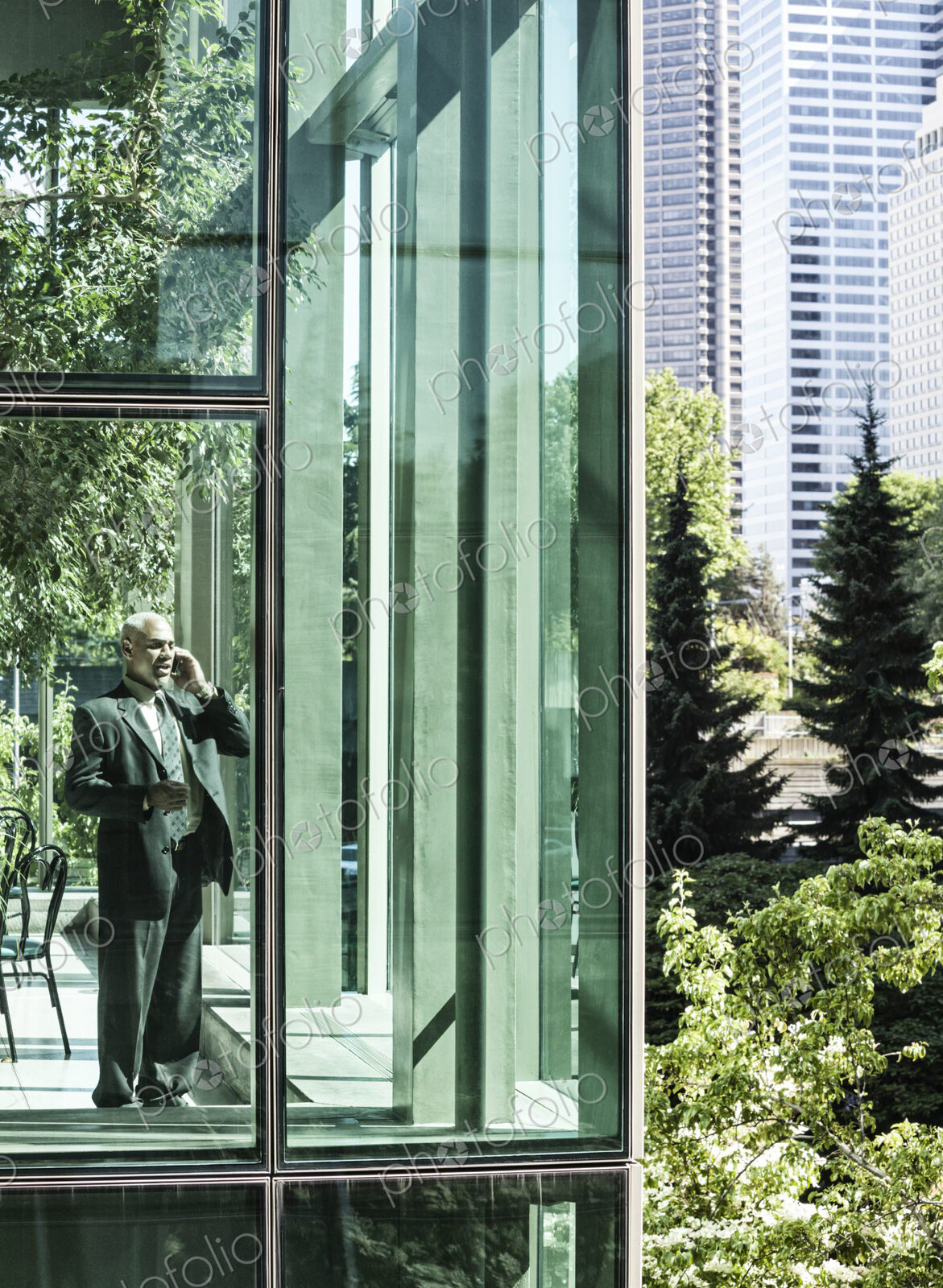 Businessman on the phone standing in a glassed in walkway.