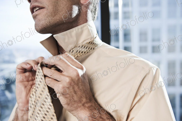 Businessman putting on a shirt and tie before work.