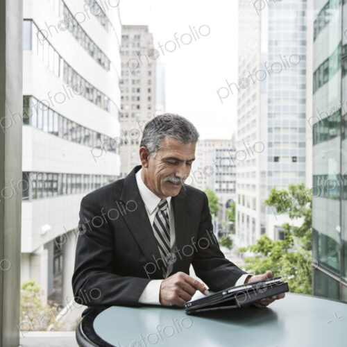 Businessman sitting in front of a window working on a notebook computer. Businessman sitting in front of a window working on a notebook computer.