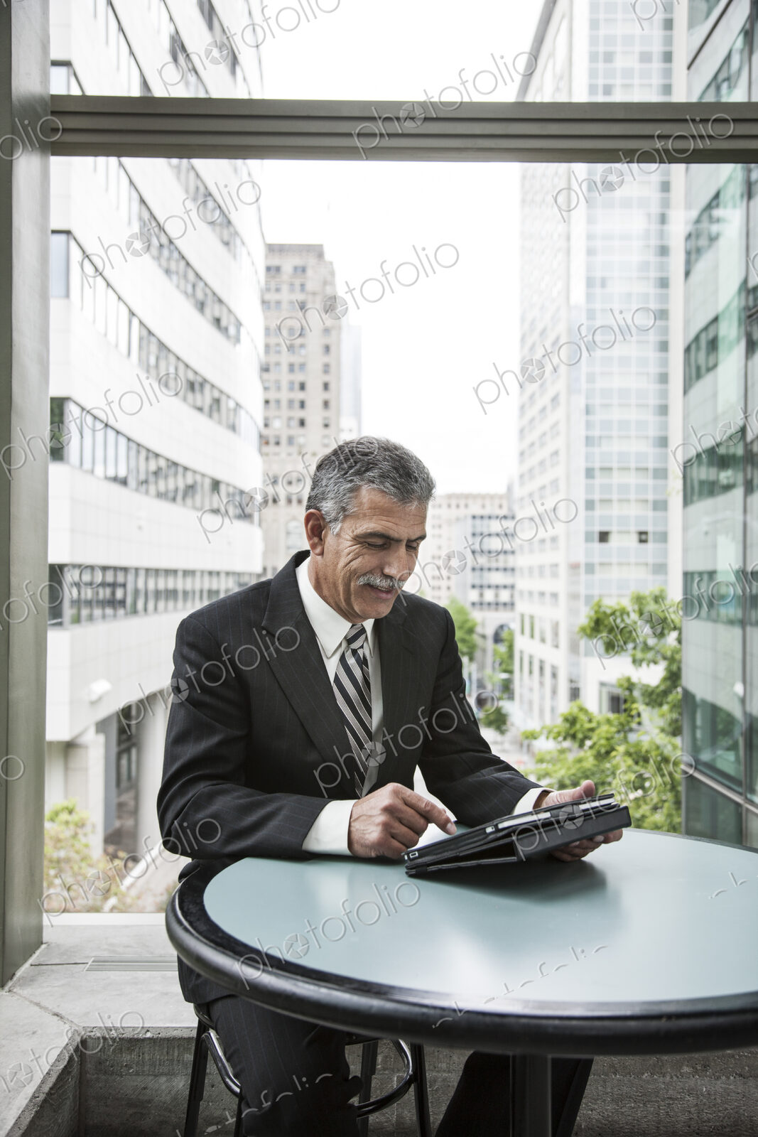 Businessman sitting in front of a window working on a notebook computer.