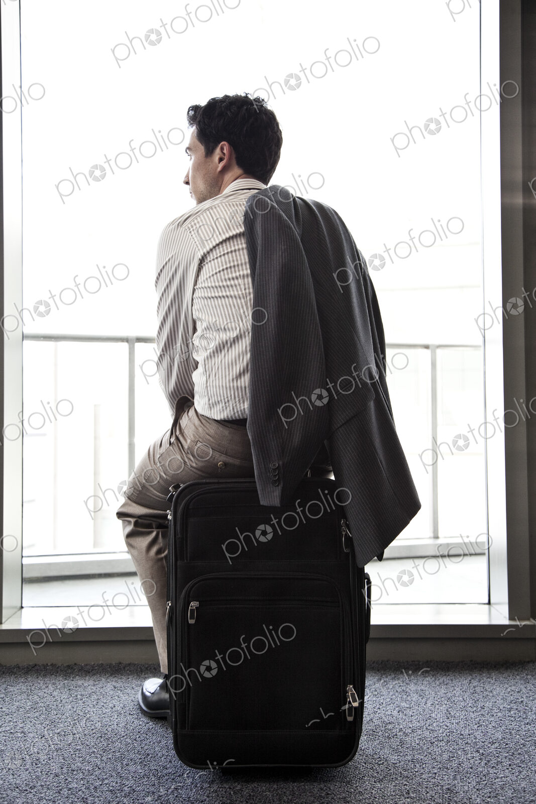 Businessman sitting on his luggage waiting for an airplane.
