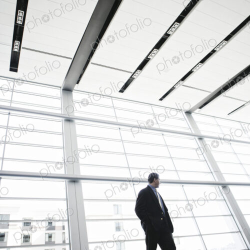 Businessman standing against a window in a conference centre lobby.
