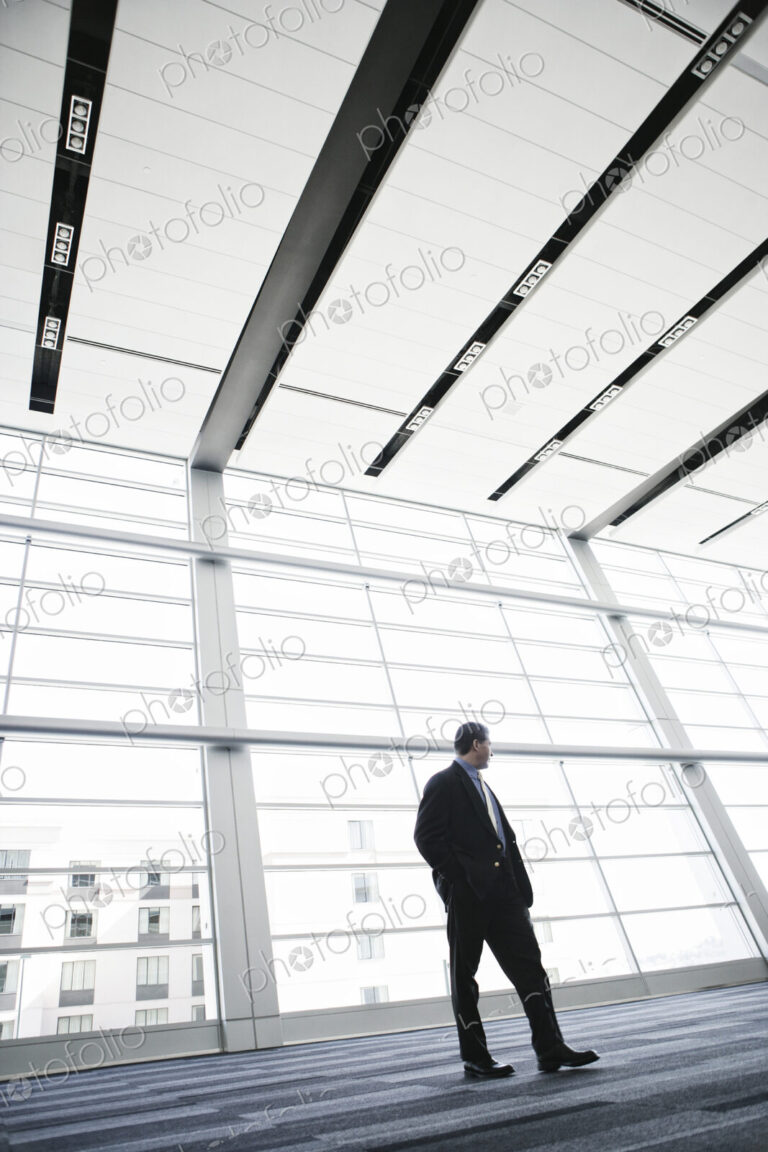 Businessman standing against a window in a conference centre lobby.