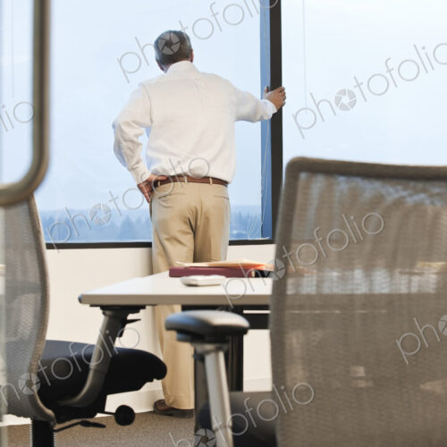 Businessman standing at a window before the next meeting in a conference room.