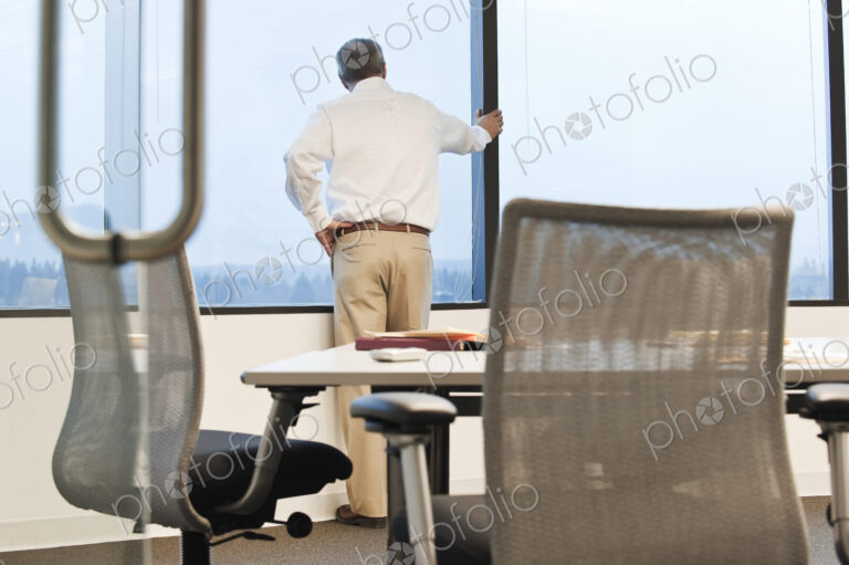 Businessman standing at a window before the next meeting in a conference room.