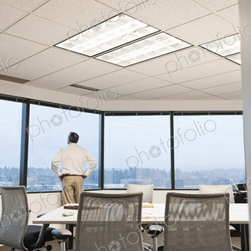 Businessman standing at a window before the next meeting in a conference room.