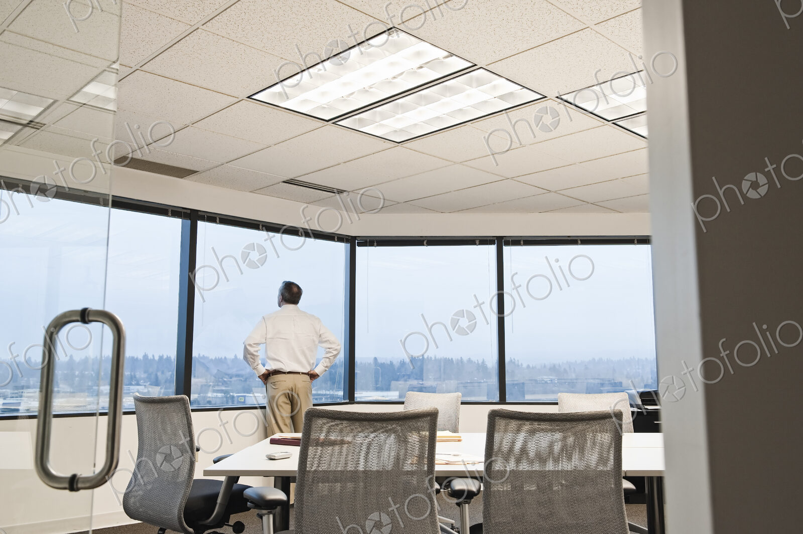 Businessman standing at a window before the next meeting in a conference room.