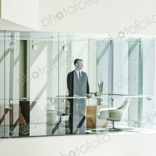Businessman standing behind a conference room window in a large business center. Businessman standing behind a conference room window in a large business center.