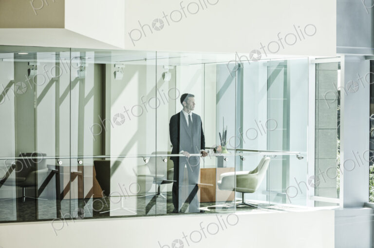 Businessman standing behind a conference room window in a large business center.