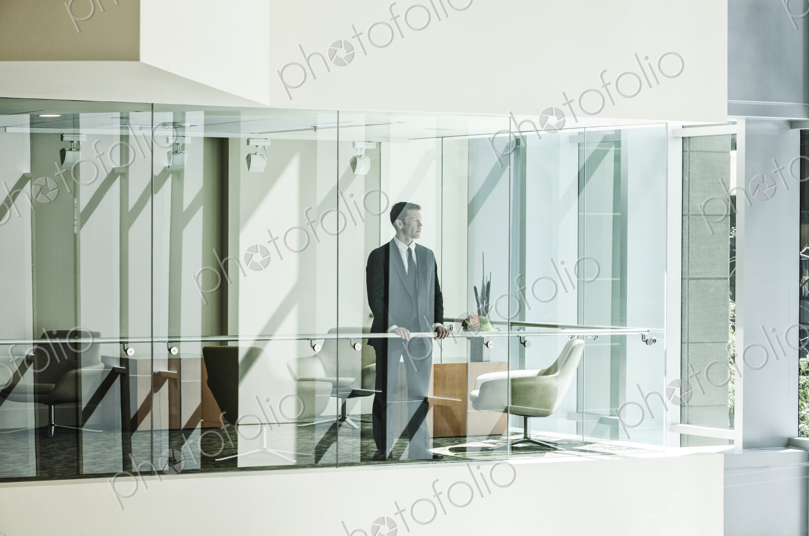 Businessman standing behind a conference room window in a large business center.
