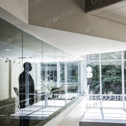 Businessman standing in a conference room window in a large business center. Businessman standing in a conference room window in a large business center.