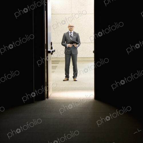 Businessman standing in a doorway between rooms in a convention center arena. Businessman standing in a doorway between rooms in a convention center arena.