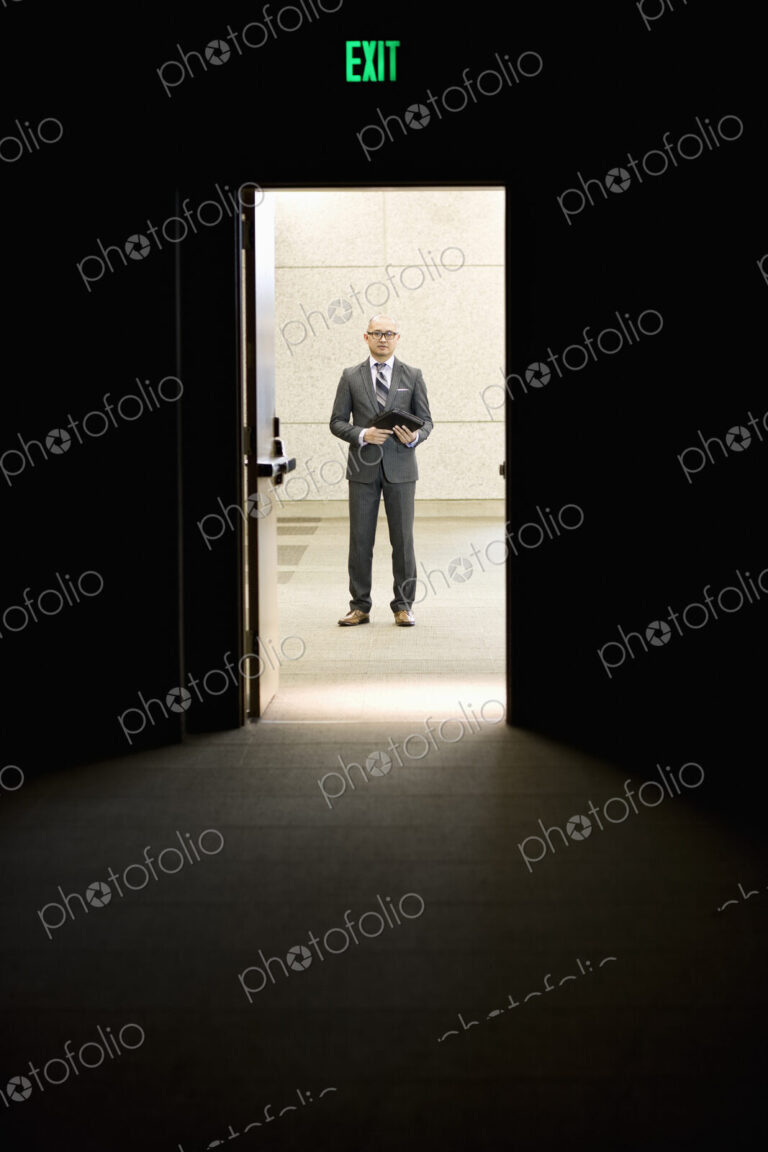 Businessman standing in a doorway between rooms in a convention center arena.