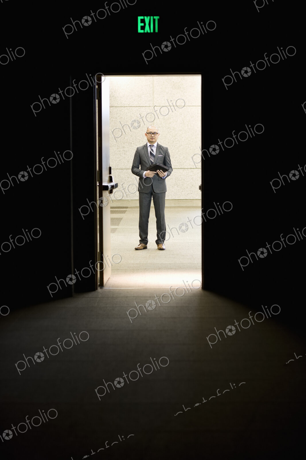 Businessman standing in a doorway between rooms in a convention center arena.