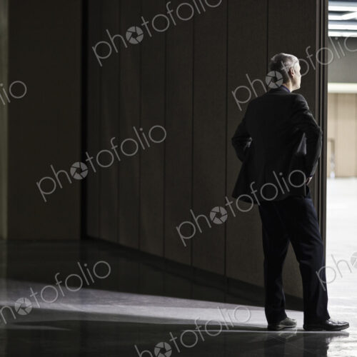 Businessman standing in a doorway between rooms in a convention center arena. Businessman standing in a doorway between rooms in a convention center arena.