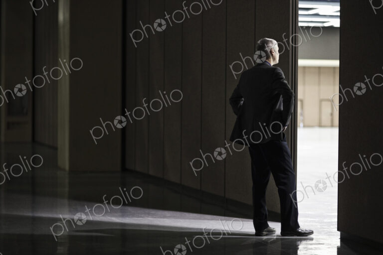 Businessman standing in a doorway between rooms in a convention center arena.