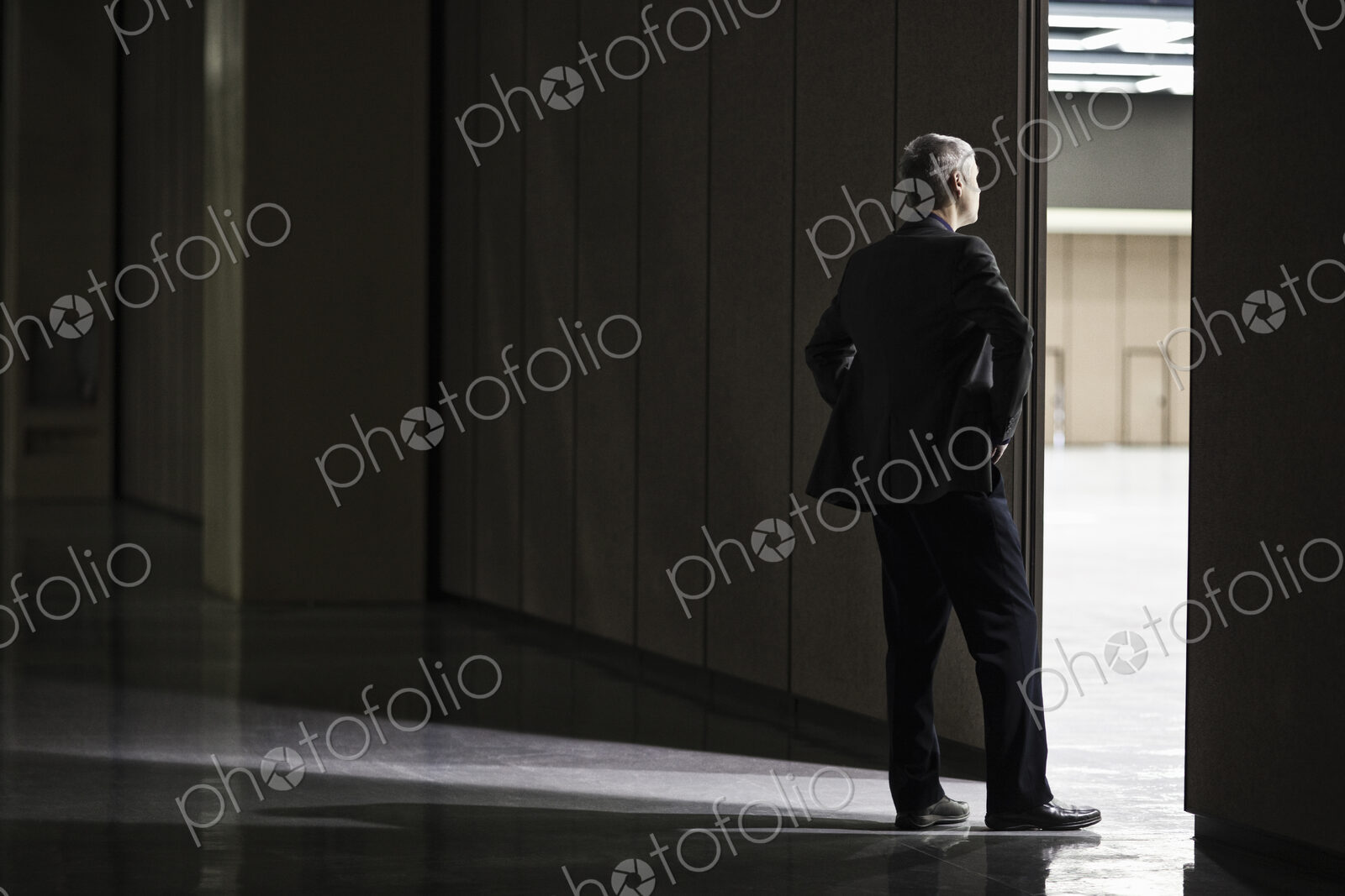 Businessman standing in a doorway between rooms in a convention center arena.