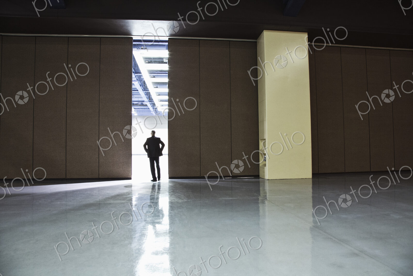 Businessman standing in a doorway between rooms in a convention center arena.