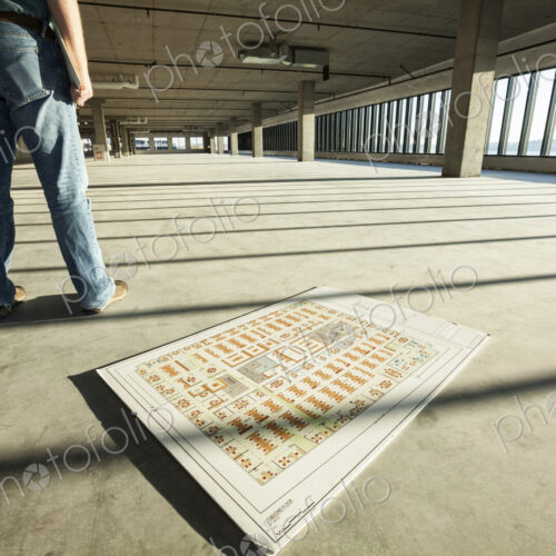 Businessman standing in the middle of an expanse of raw space, and architectural plans… Businessman standing in the middle of an expanse of raw space, and architectural plans…