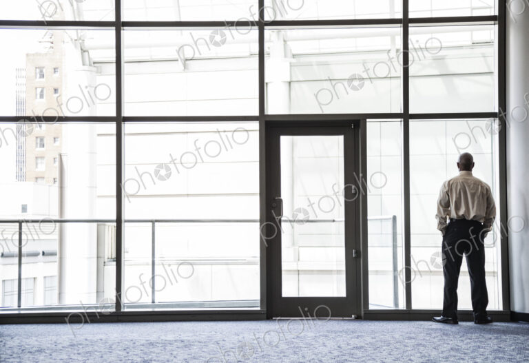 Businessman standing looking through a window in a large lobby area