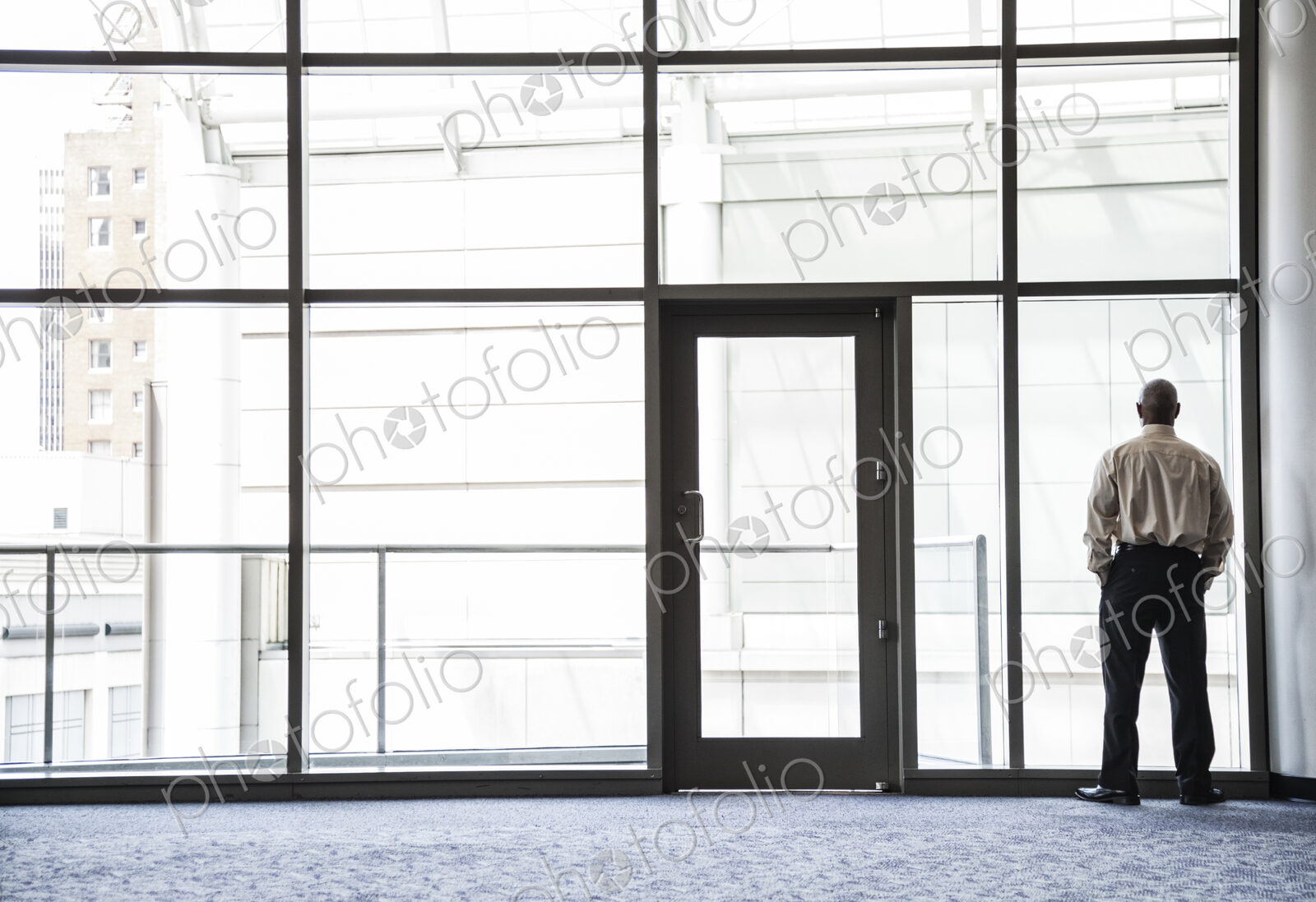 Businessman standing looking through a window in a large lobby area