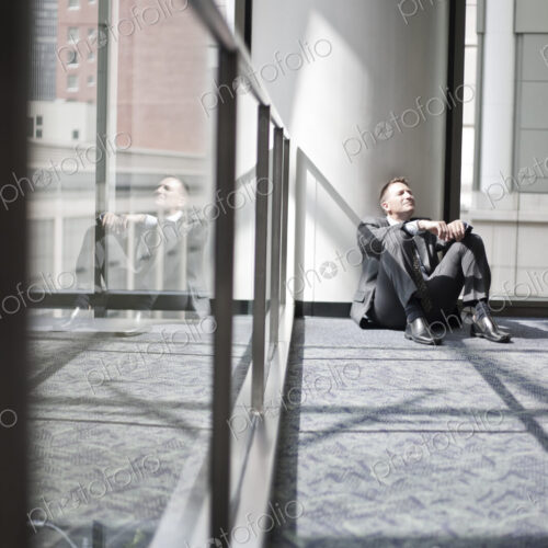 Businessman taking a break sitting on the floor by a window