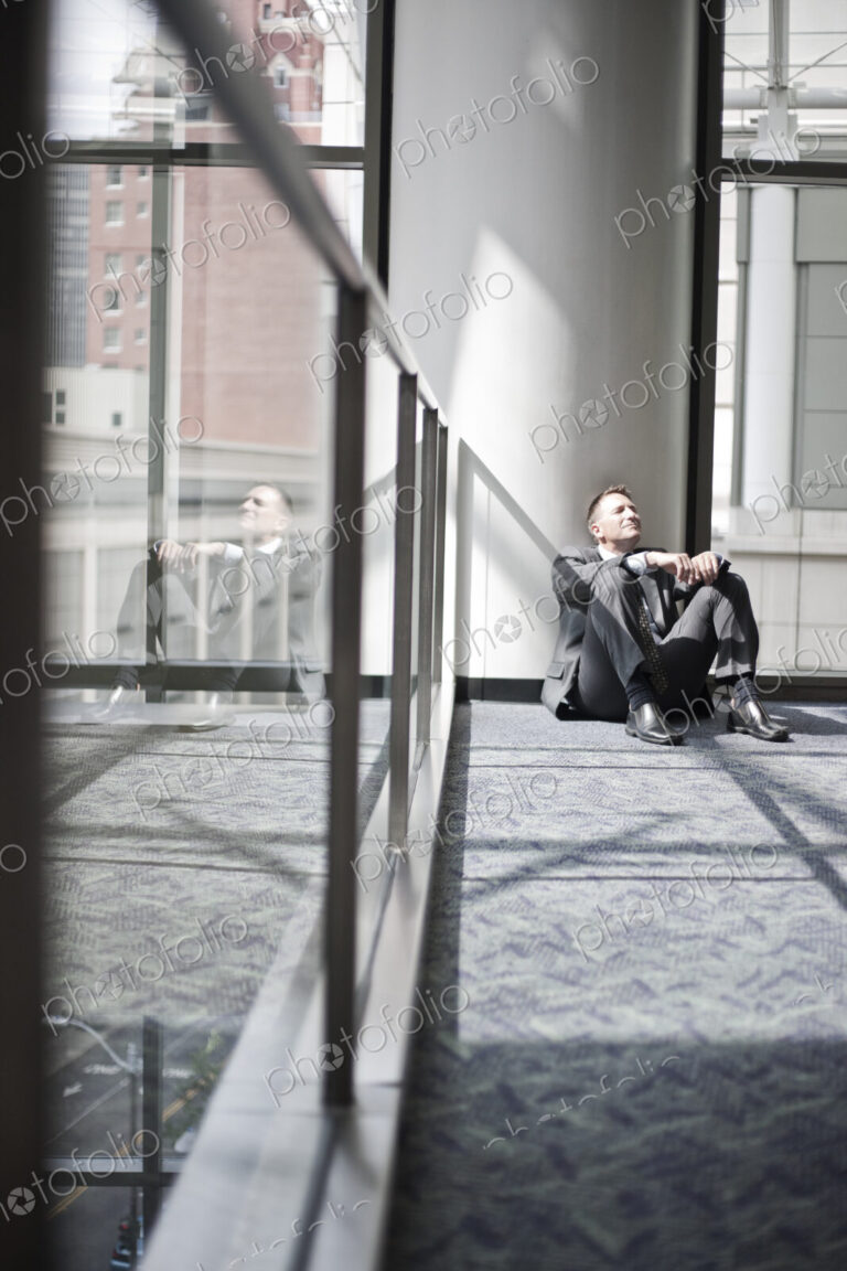 Businessman taking a break sitting on the floor by a window