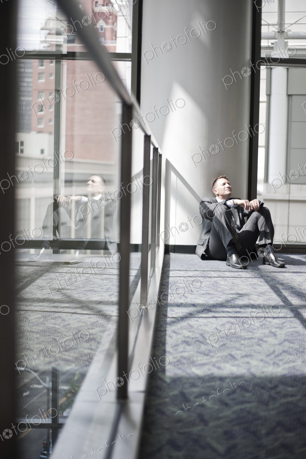 Businessman taking a break sitting on the floor by a window