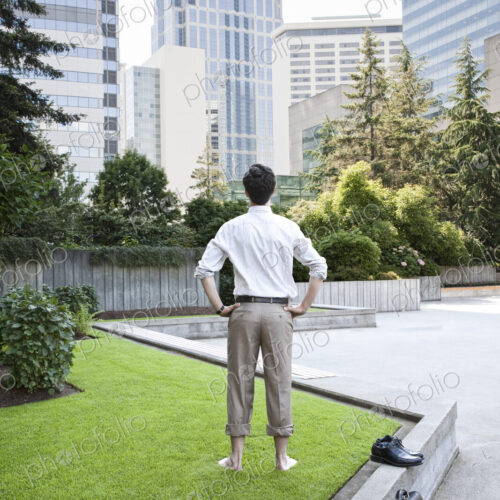 Businessman taking a break standing barefoot in a downtown city park.
