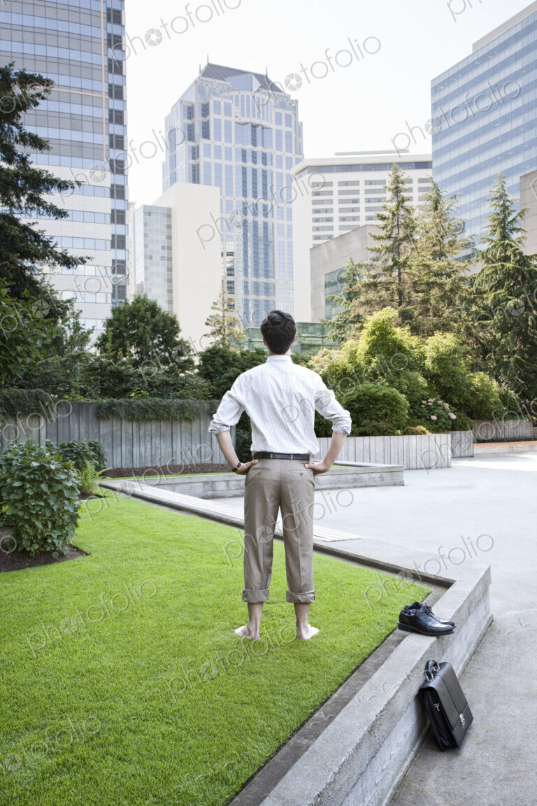 Businessman taking a break standing barefoot in a downtown city park.