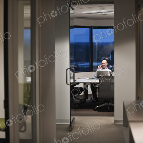 Businessman talking on the phone while working at night Businessman talking on the phone while working at night