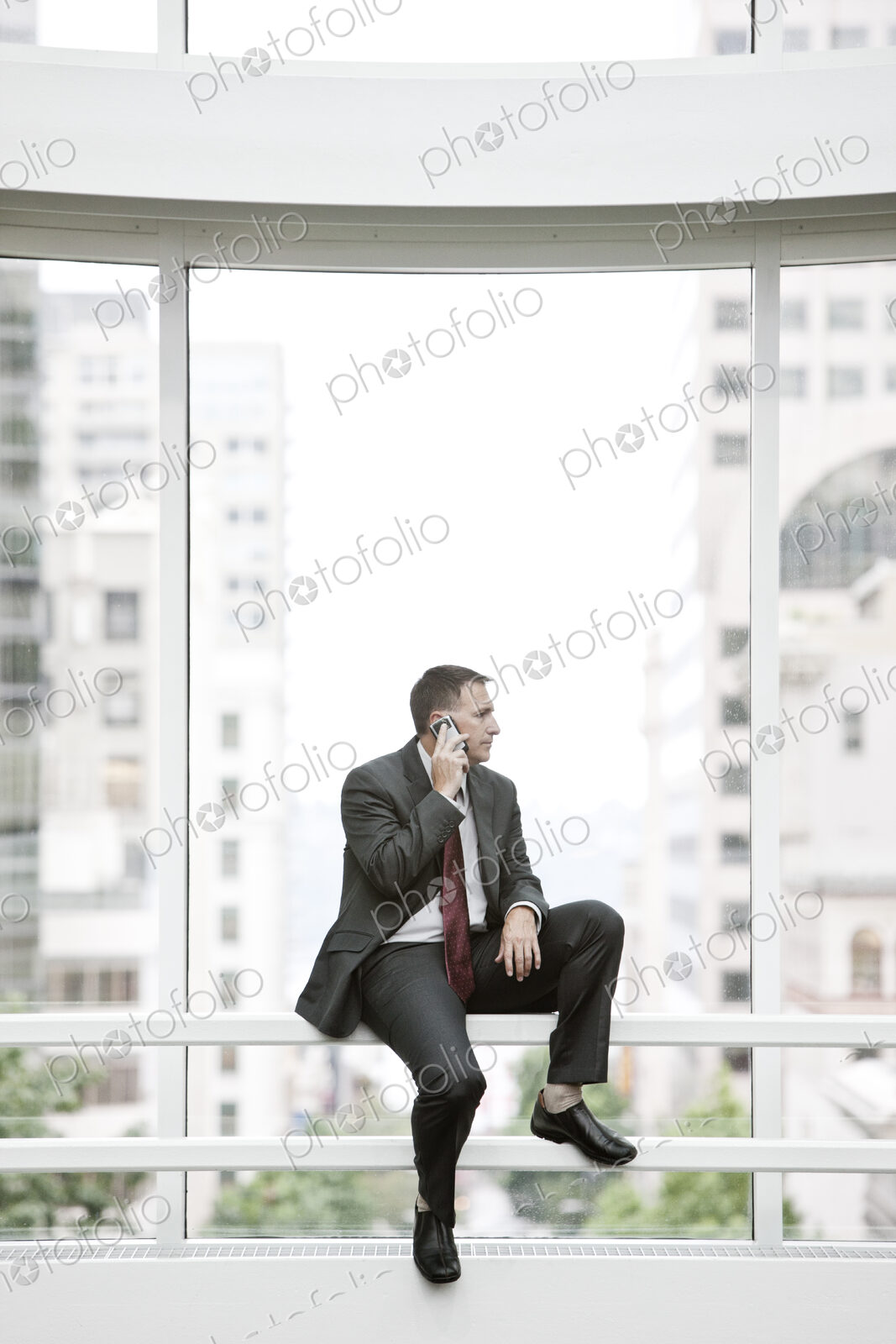 Businessman using his phone sitting on a railing