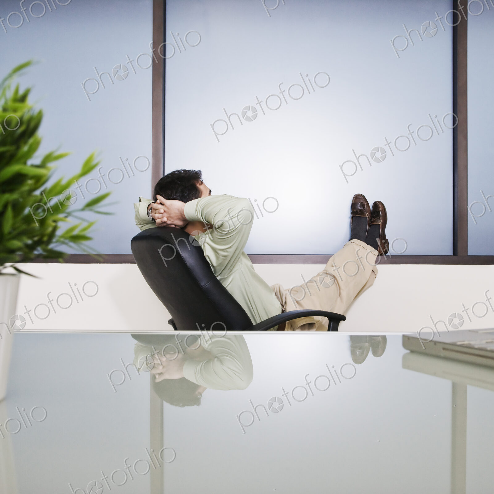 Businessman with his feet up relaxing at this desk in his office.