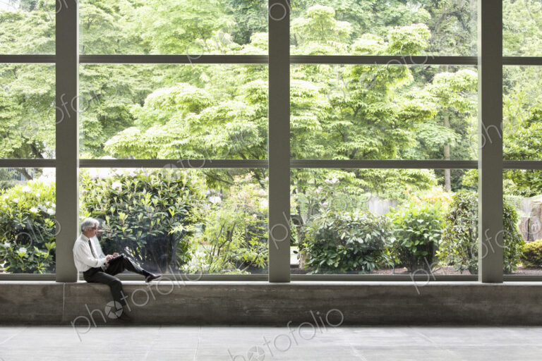 Businessman working on a notebook computer in front of a large window in a convention…