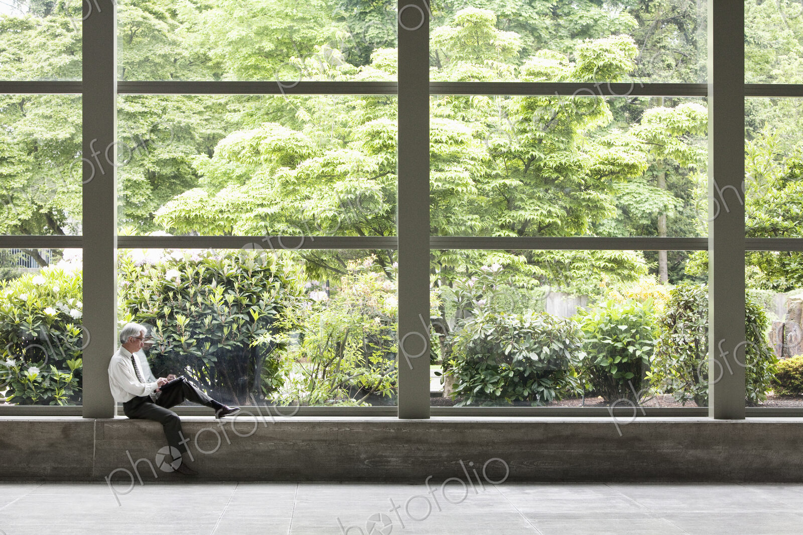 Businessman working on a notebook computer in front of a large window in a convention…
