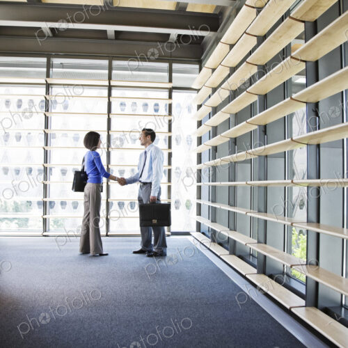 Businesswoman and busiinessman working in a lobby of a large office building.