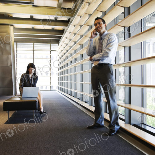 Businesswoman and businessman working in a lobby of a large office building.