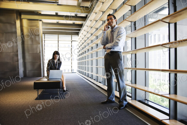 Businesswoman and businessman working in a lobby of a large office building.
