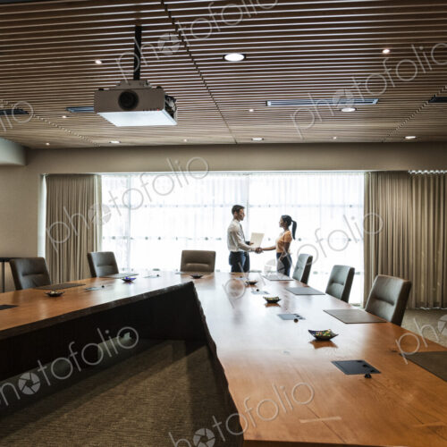 Businesswoman and man meeting in a large conference room.