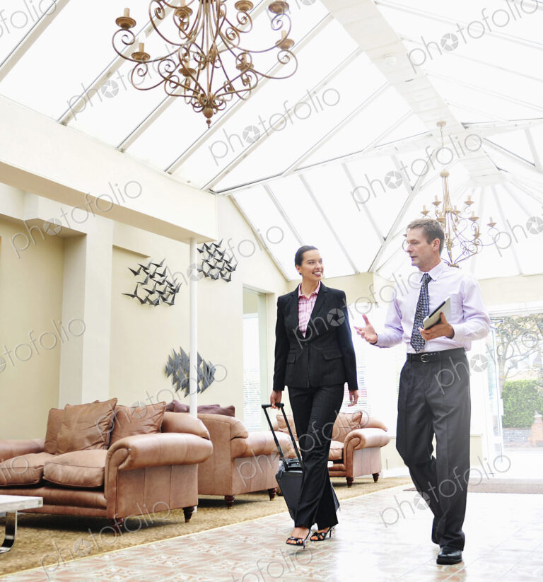 Businesswoman and man walking through hotel lobby, business travel.