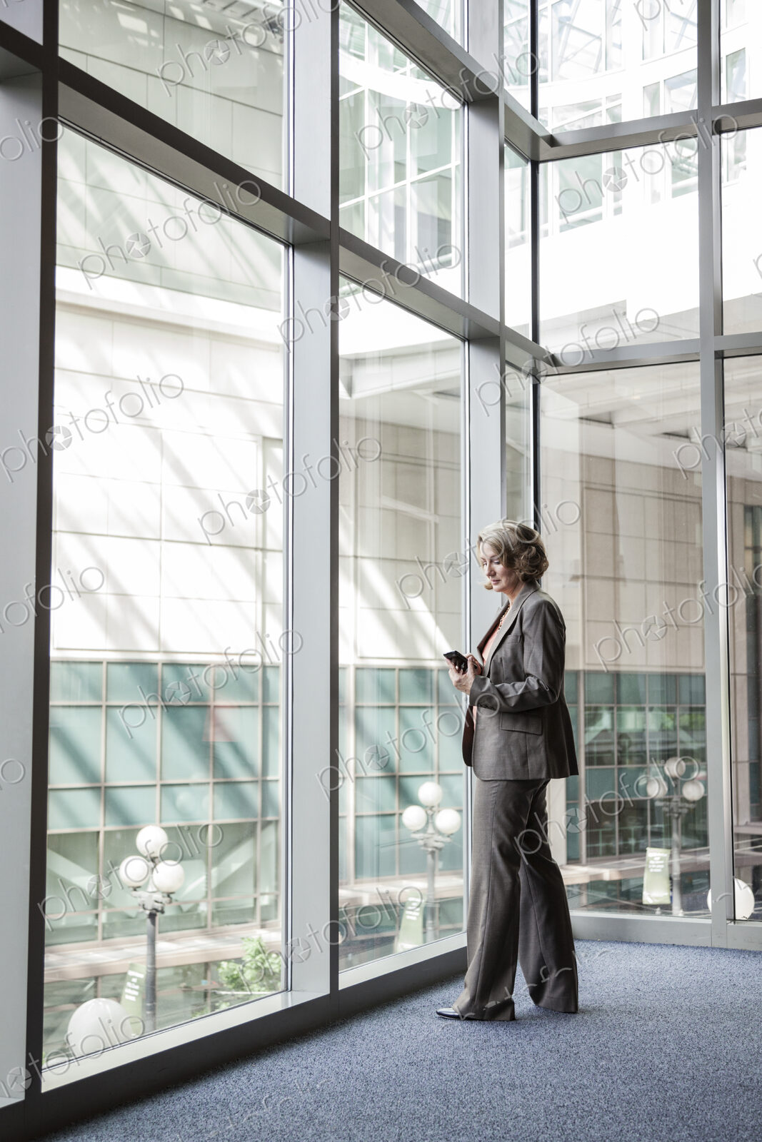 Businesswoman checking her cell phone for messages by a window