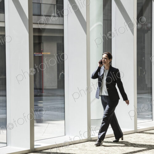 Businesswoman on the phone and walking through the lobby of a large business center. Businesswoman on the phone and walking through the lobby of a large business center.